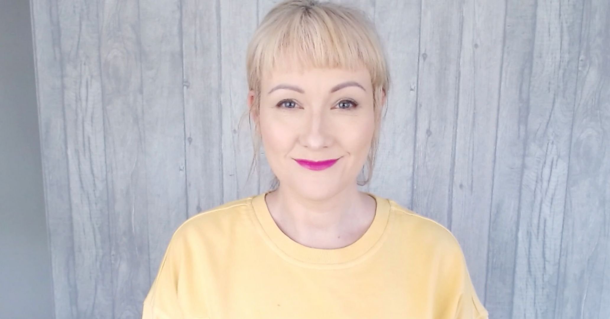 Image of Nicola in a yellow jumper smiling to the camera